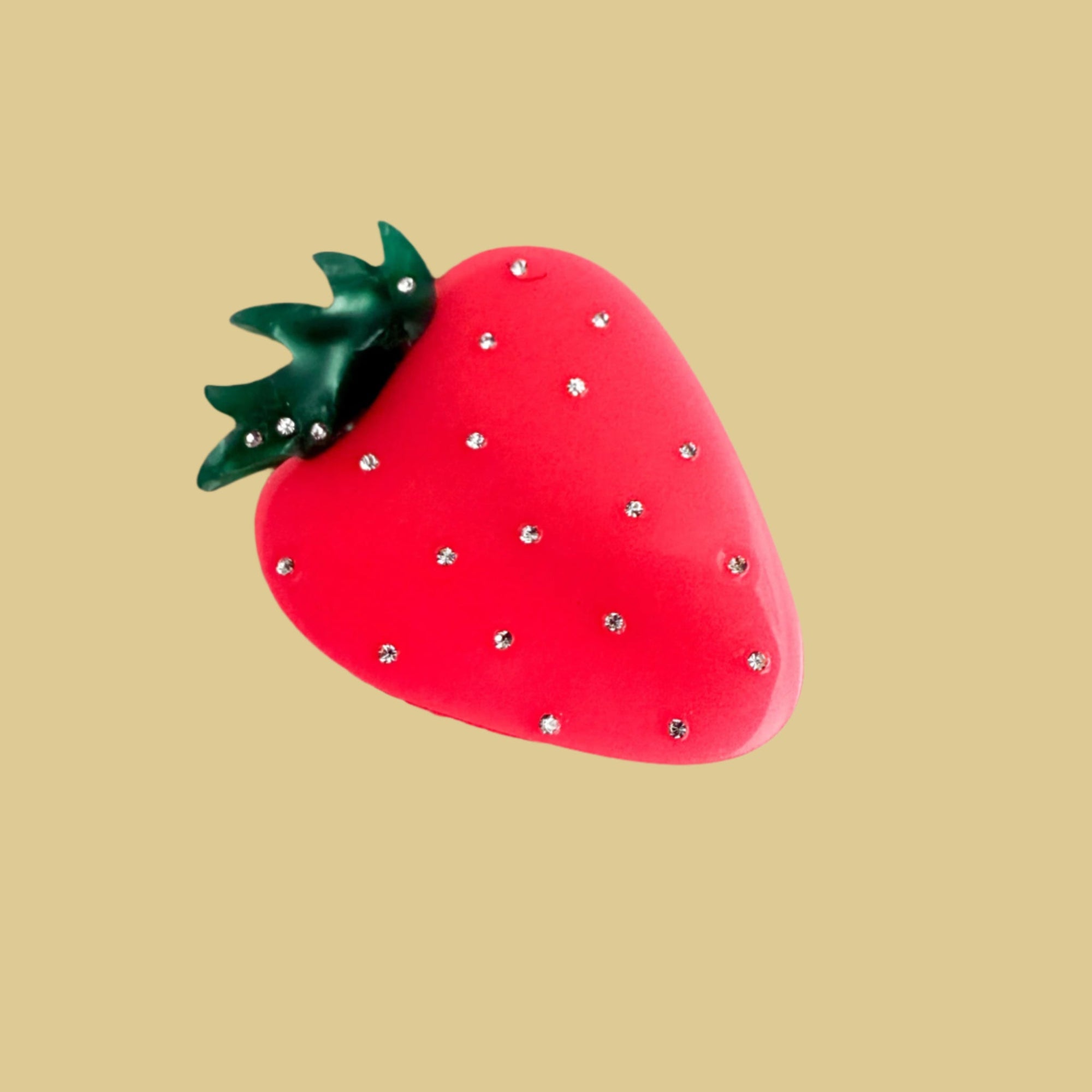 Strawberry-shaped object with rhinestones on a white background