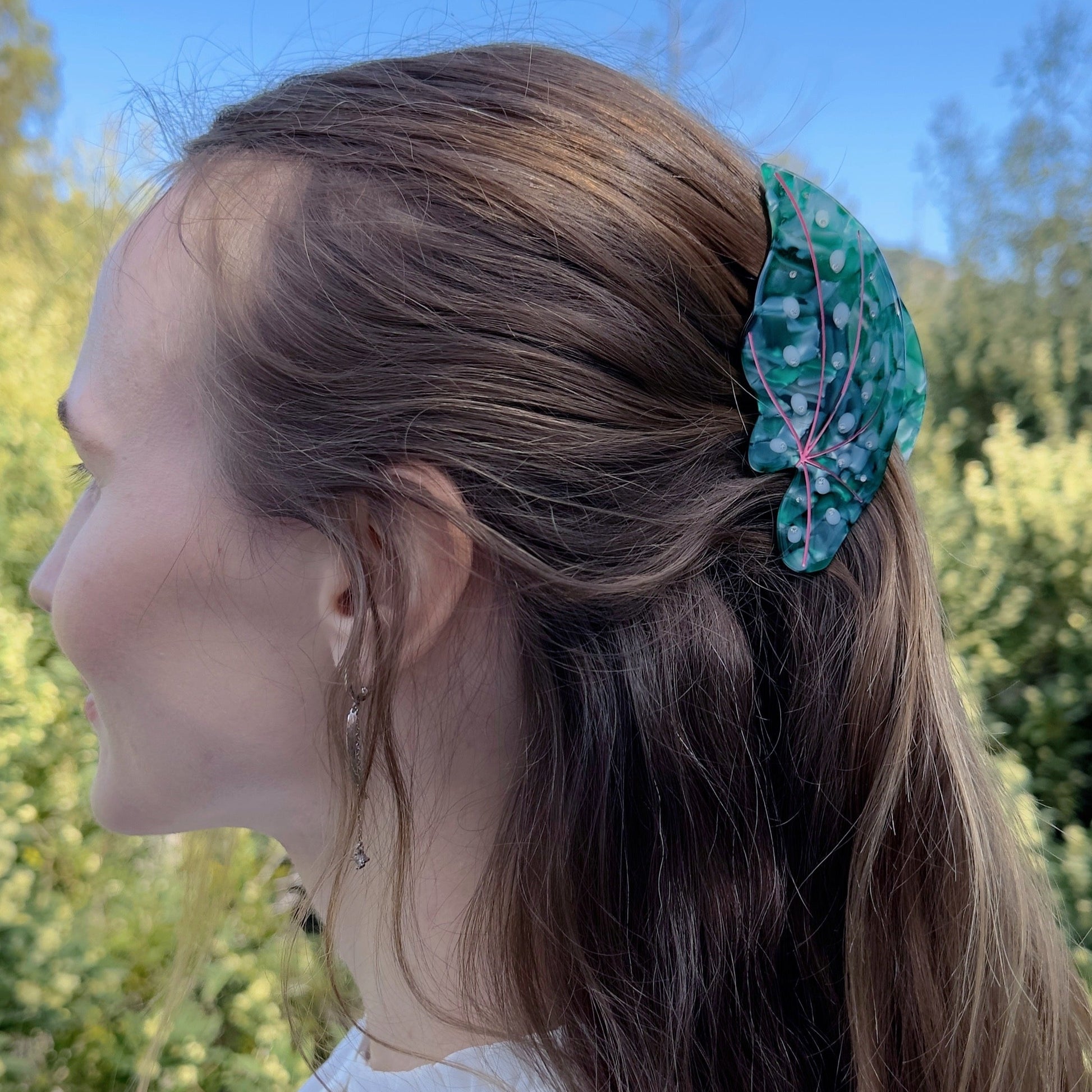 A hair claw in the shape of a green leaf on gray hair.