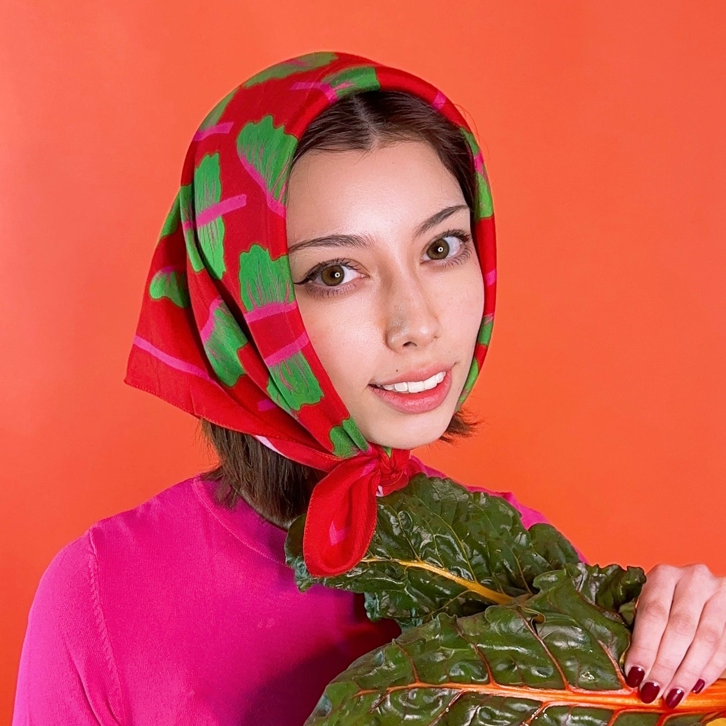 Red silk scarf with green chard and pink details.