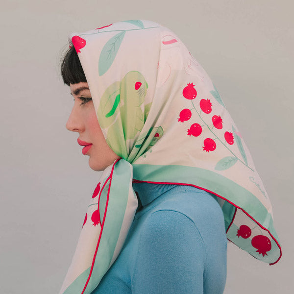 Woman wearing multicolored silk bandana on tan background.