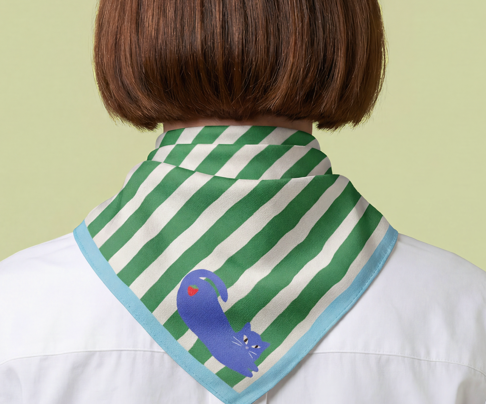 woman wearing a green and white striped scarf with a blue cat and strawberry, with cyan blue border, on a light green background