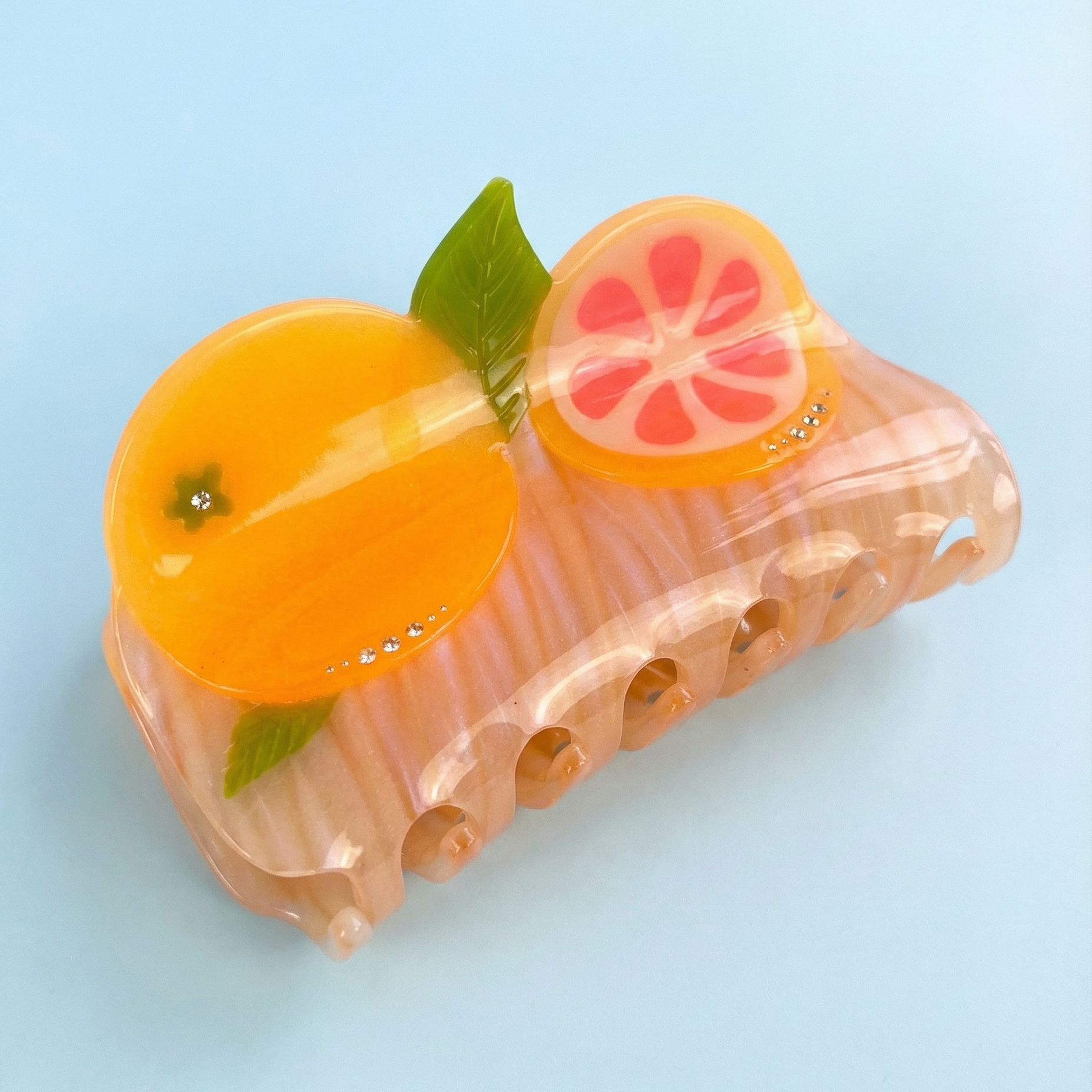 fruit-themed hair claw with orange and grapefruit slices on a light blue background