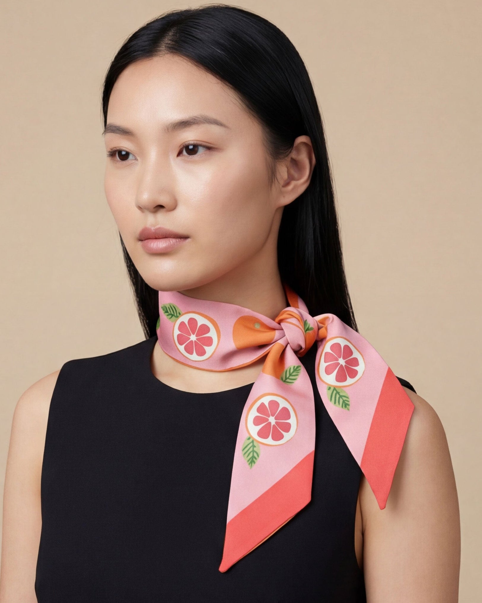 Woman wearing a pink scarf with orange fruit design on a beige background