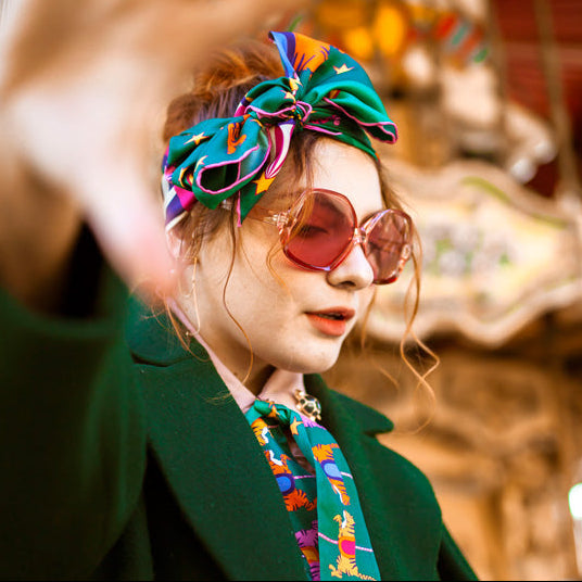 Woman wearing green jacket and neon tiger silk scarf.