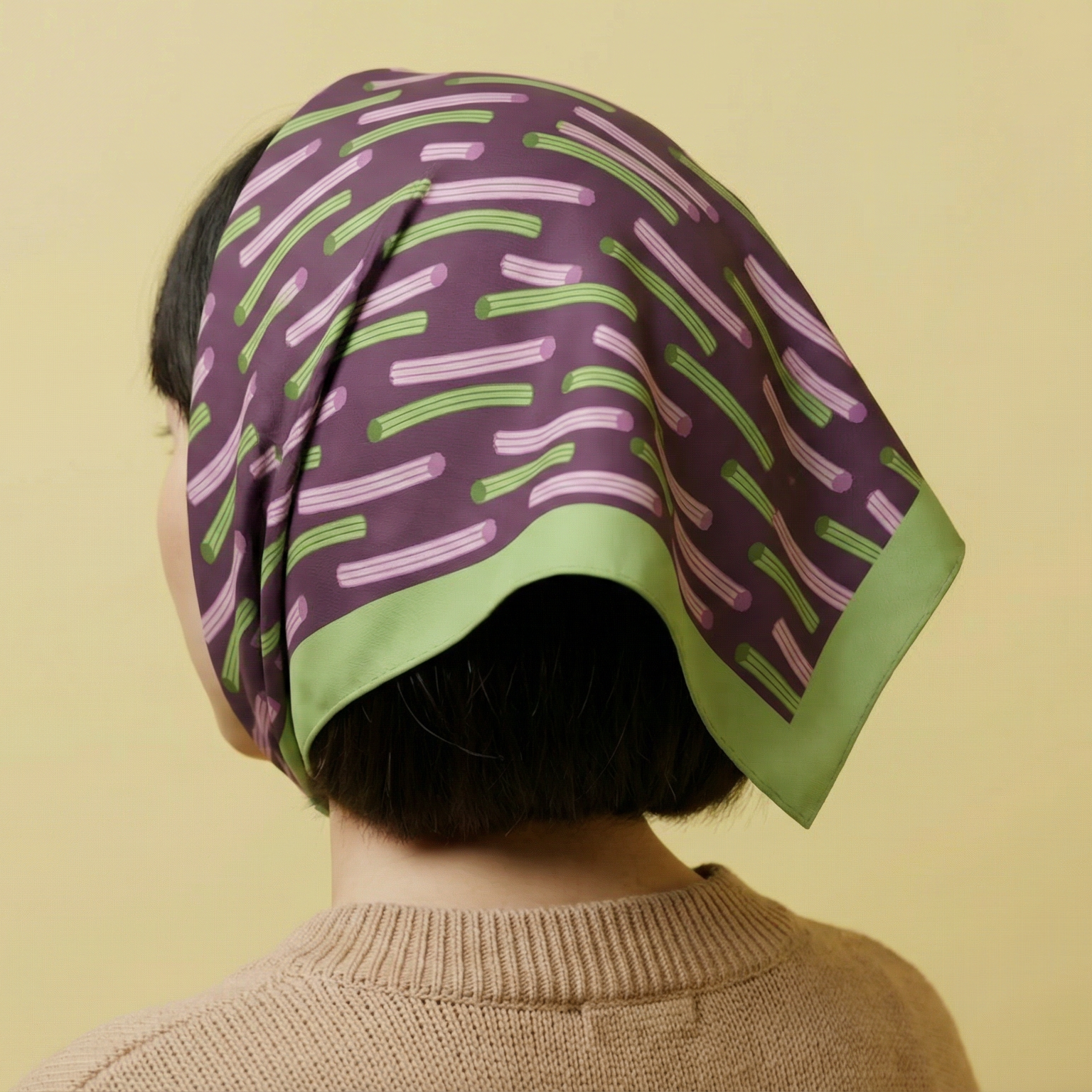 Girl wearing a Churros Inspired cotton silk blend bandana twill woven on purple and green  headscarf on a yellow background