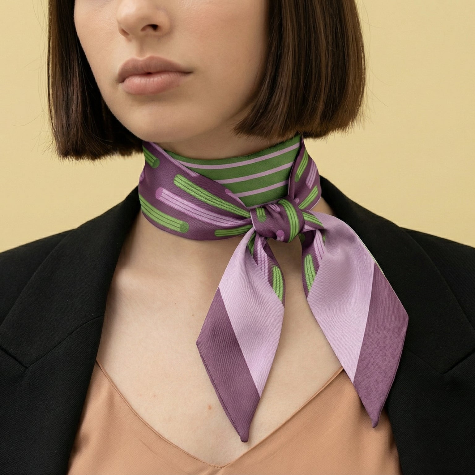 Woman wearing a purple and green churros inspired scarf around her neck against a beige background