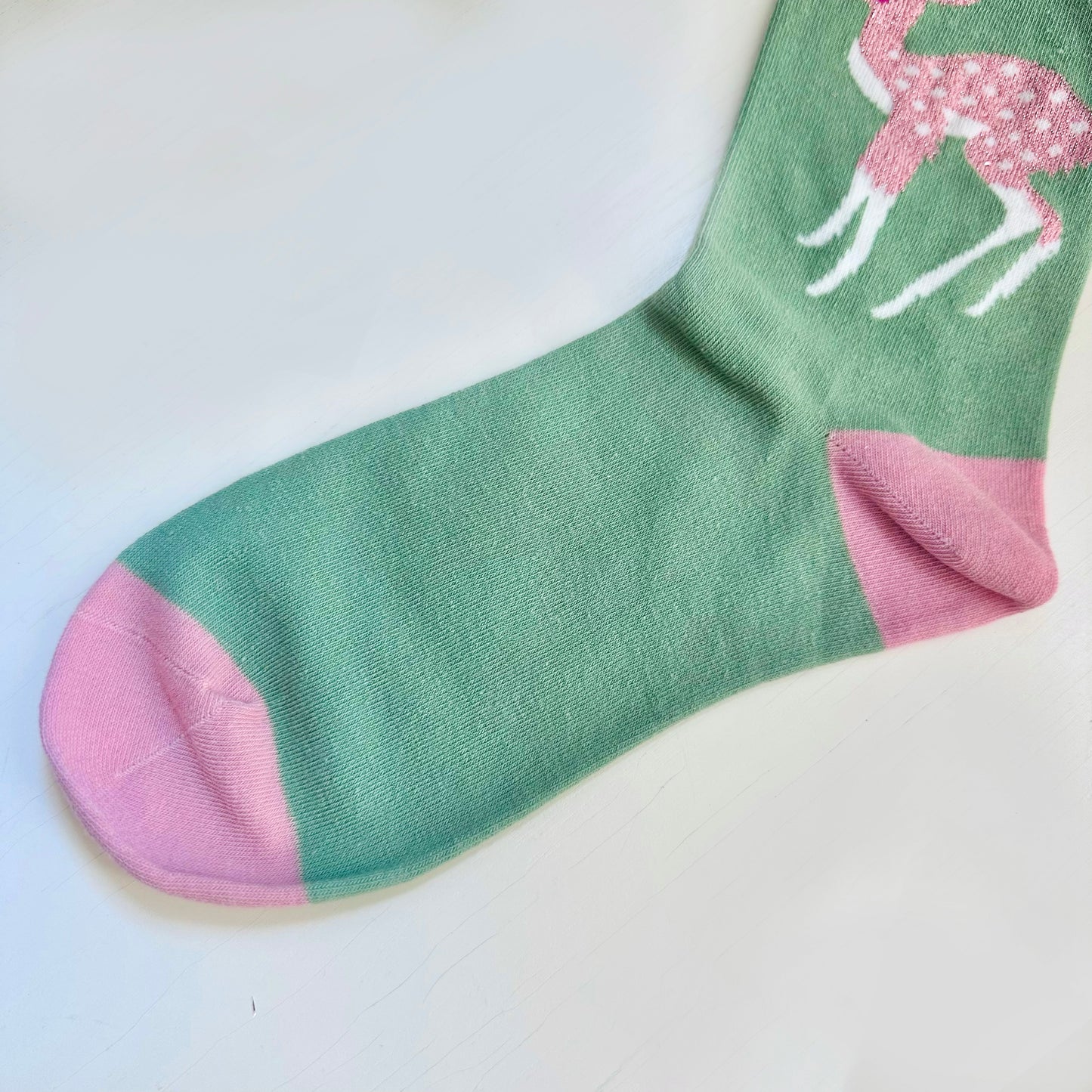 A green and pink sock with a deer on it.