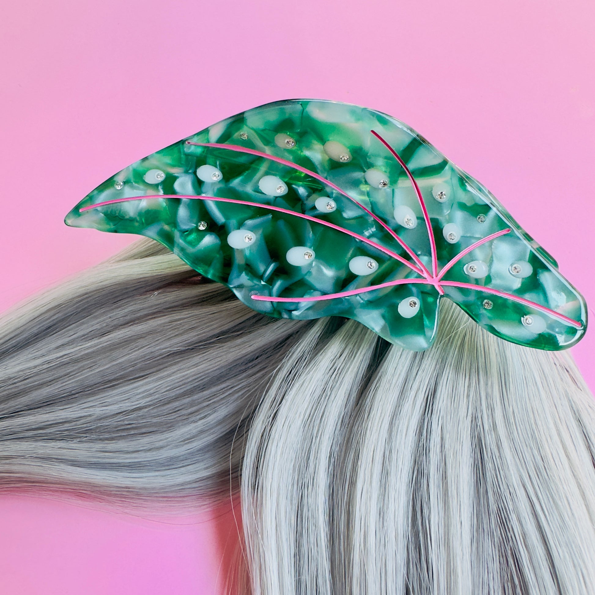 A hair claw in the shape of a green leaf on gray hair.