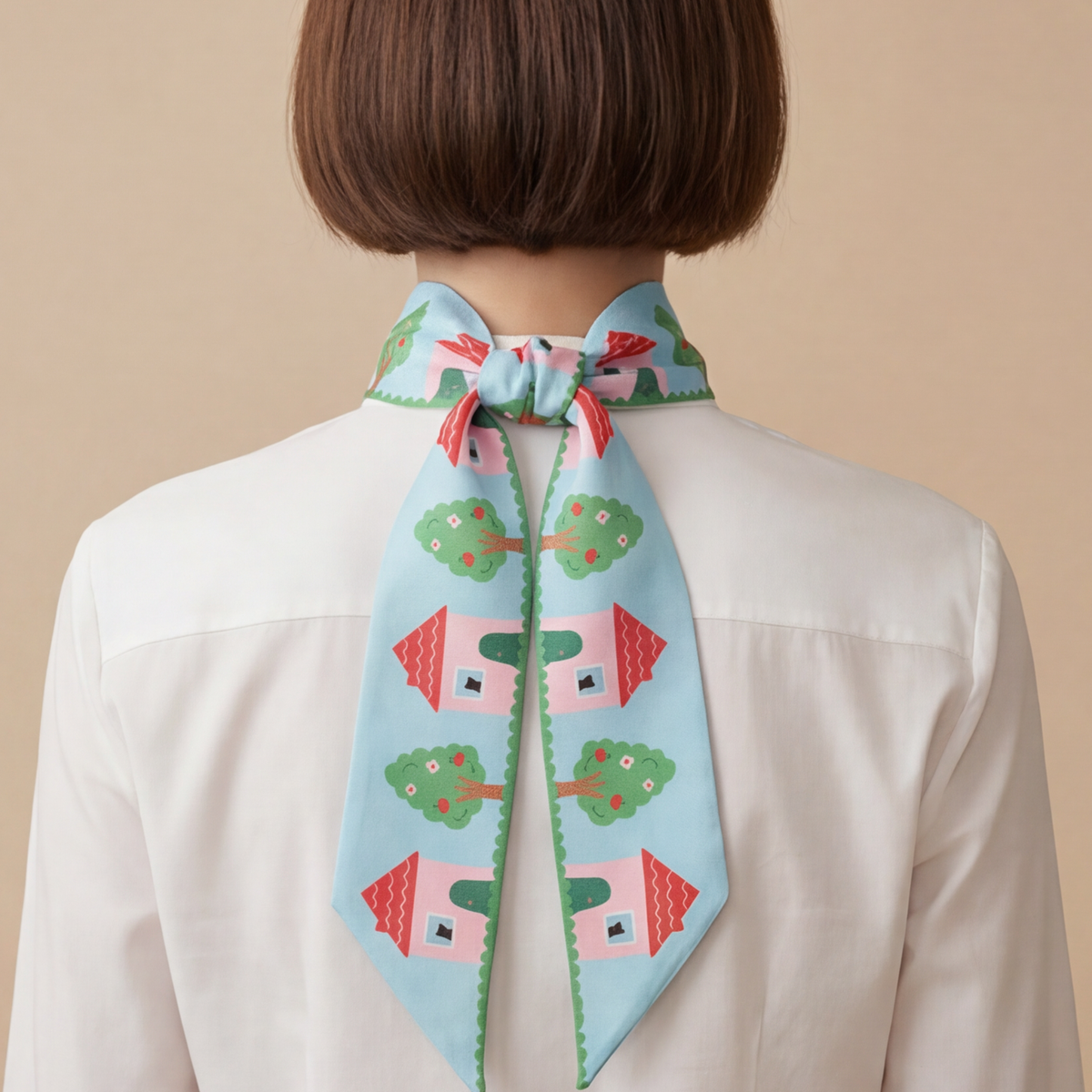 Person wearing a colorful house with treess apples twilly silk scarf on a beige background