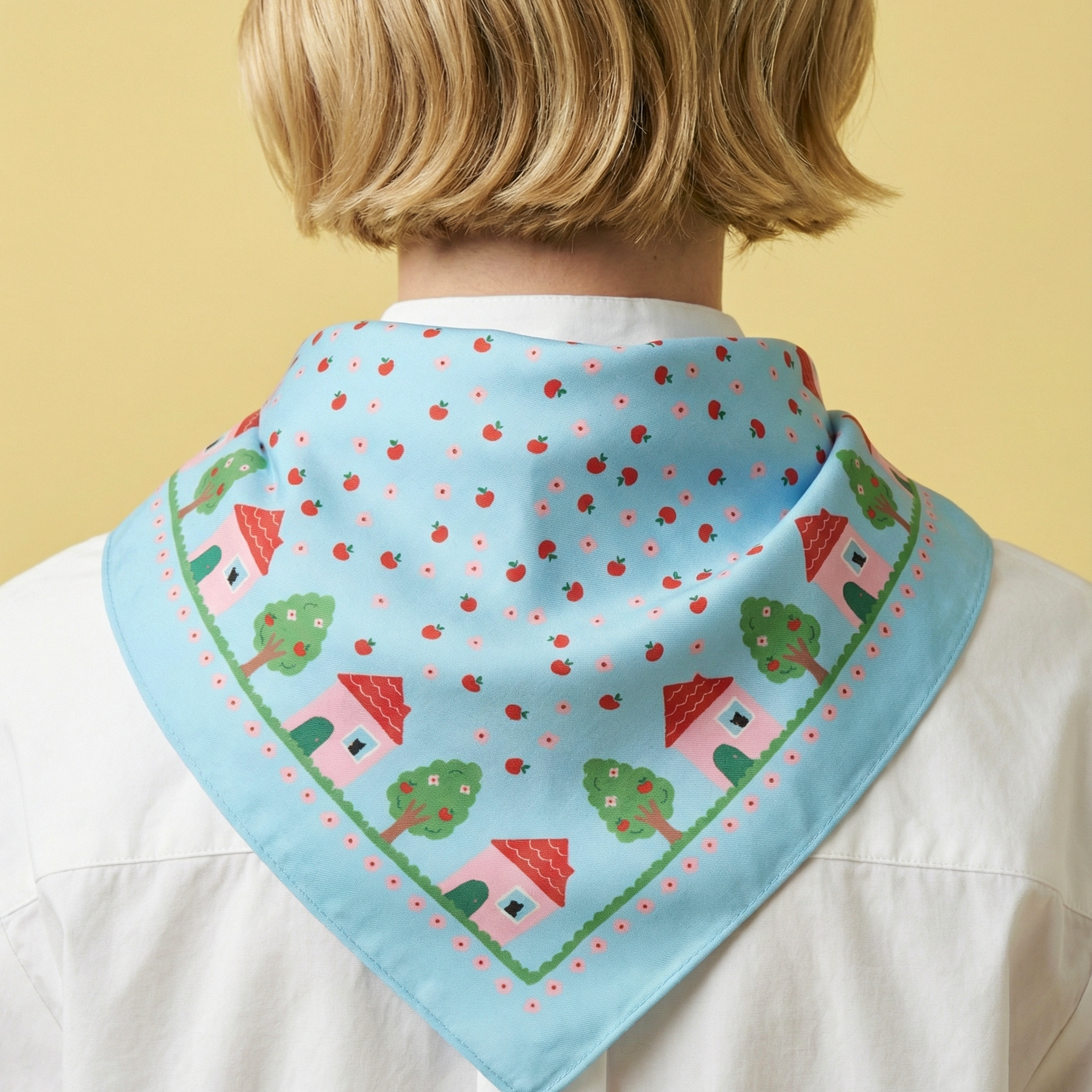 Person wearing a light blue bandana with house pattern on a yellow background