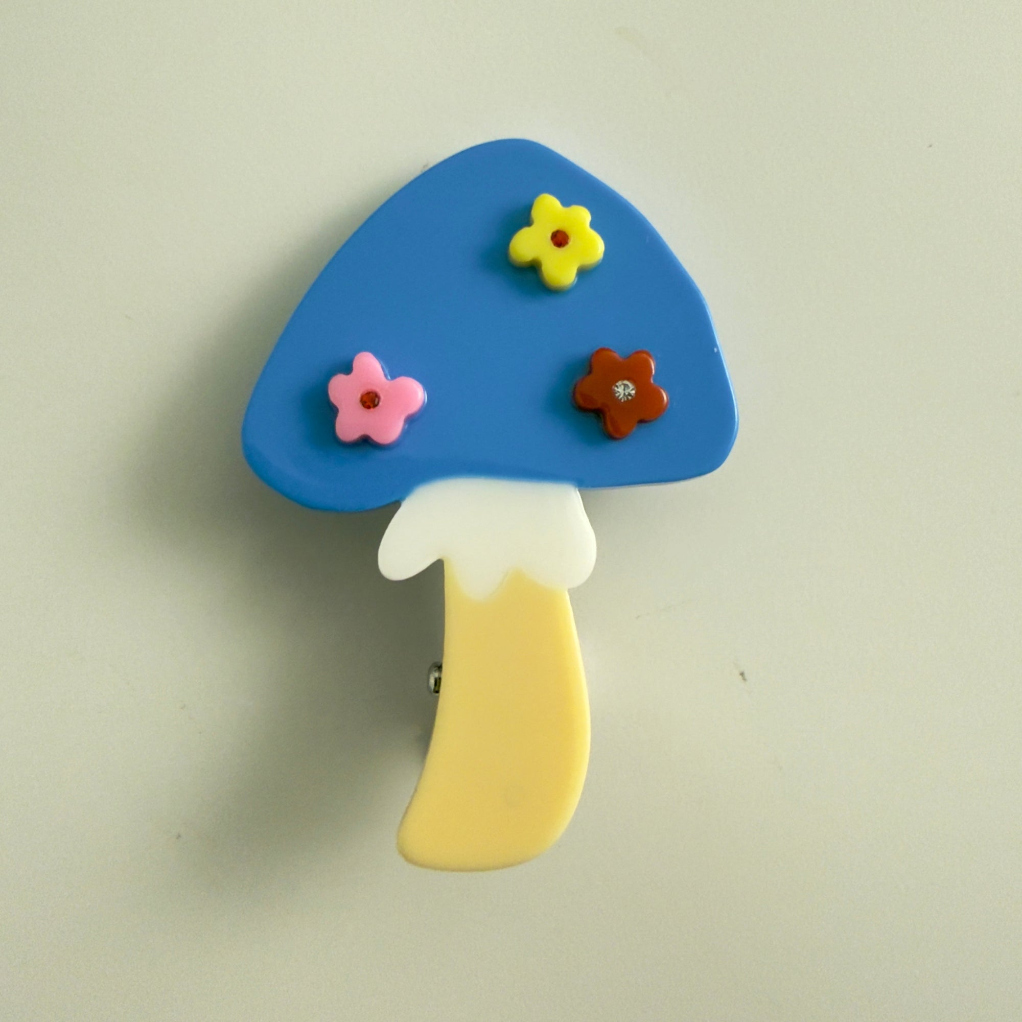 Colorful mushroom-shaped hair clip with flowers on a beige background