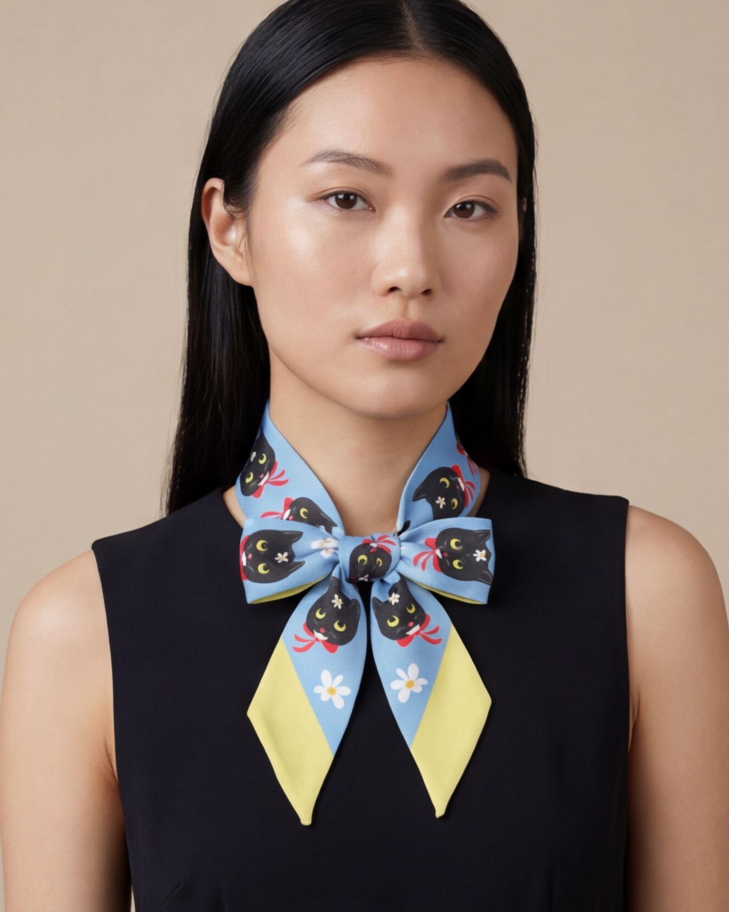 Woman wearing a colorful with tuxedo cats silk twilly scarf around her neck against a beige background