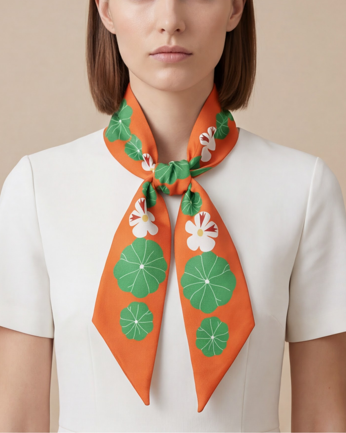 Woman wearing an orange and green twilly silk scarf with green and nasturtion floral patterns on a beige background