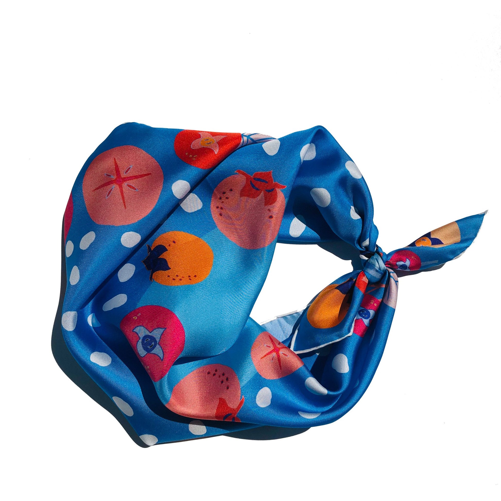 A blue tied silk bandana with persimmons and white polka dots.