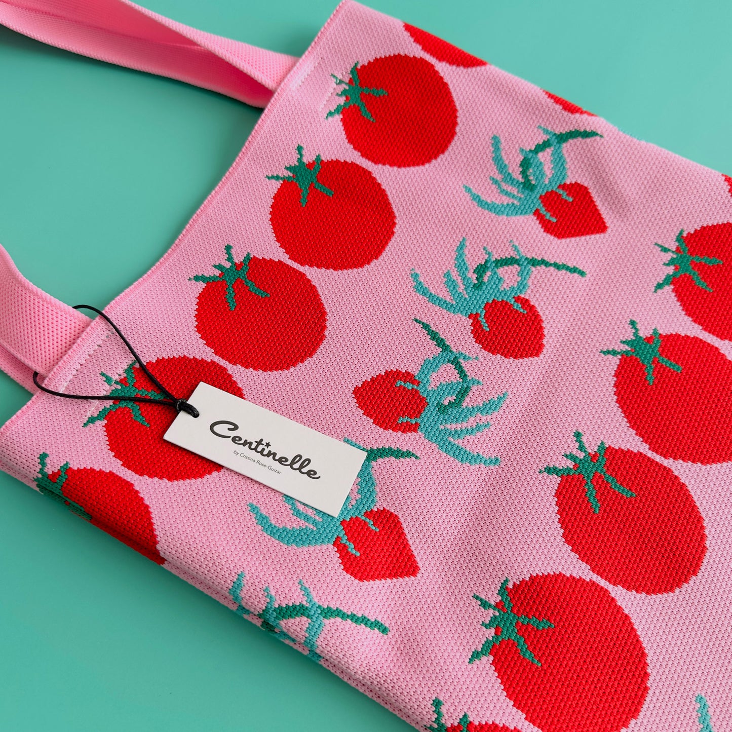 A pink centinelle tote bag with tomatoes on it.