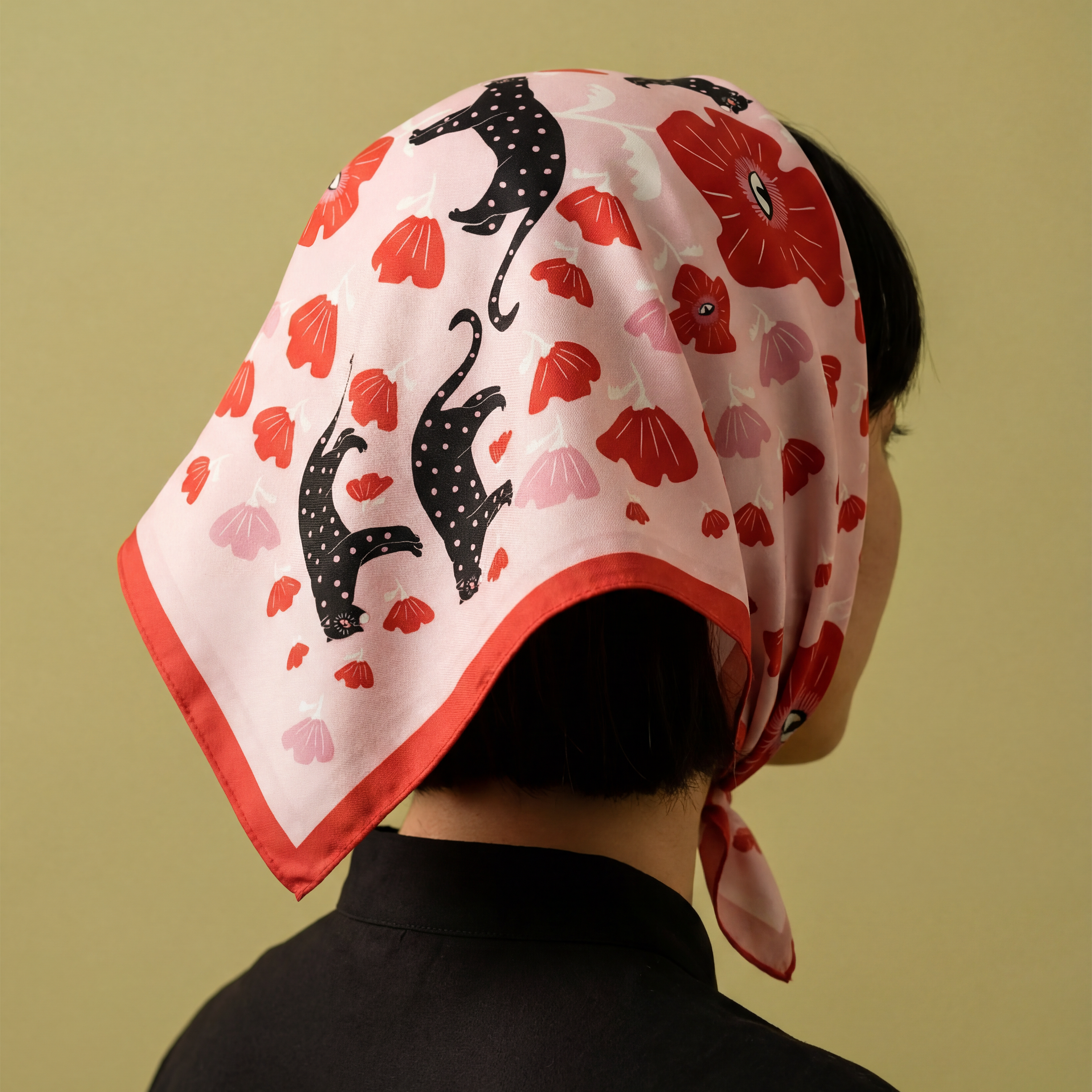 woman wearing a headscarf with red flowers and black panther cat with polka dots on a yellow background