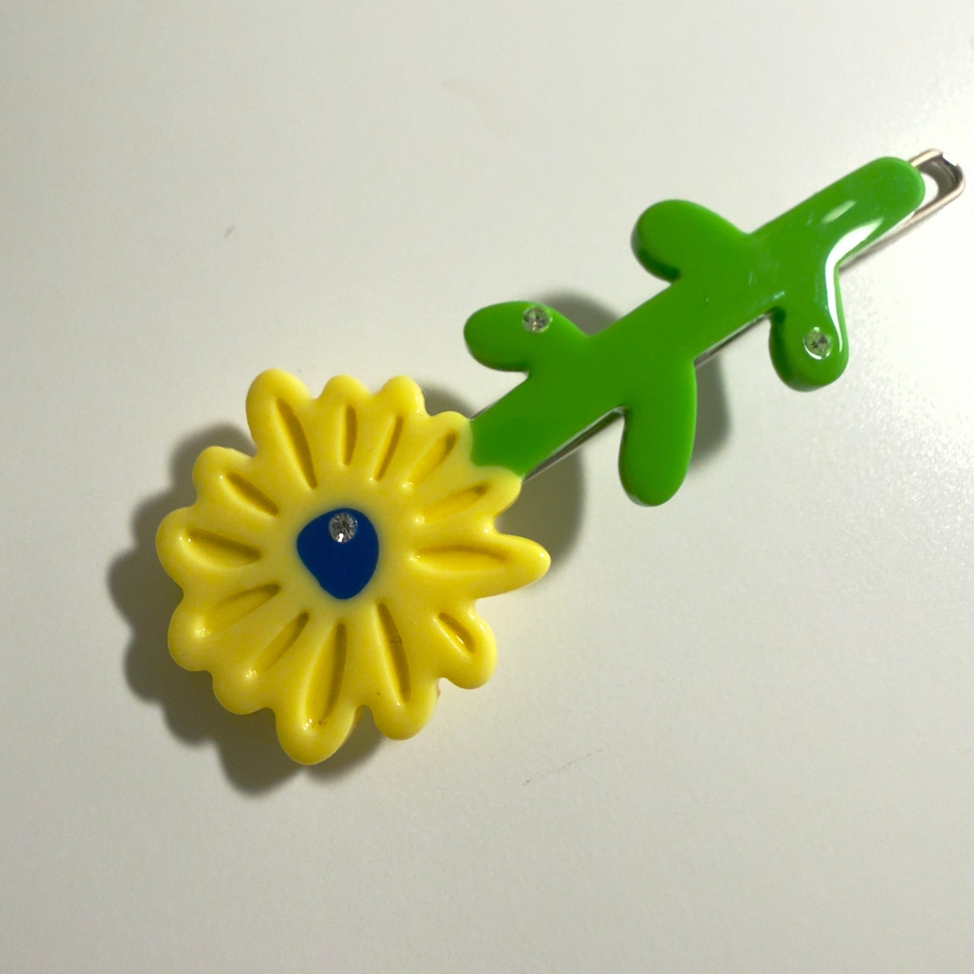 Hair clip with yellow flower and green leaves on a white background