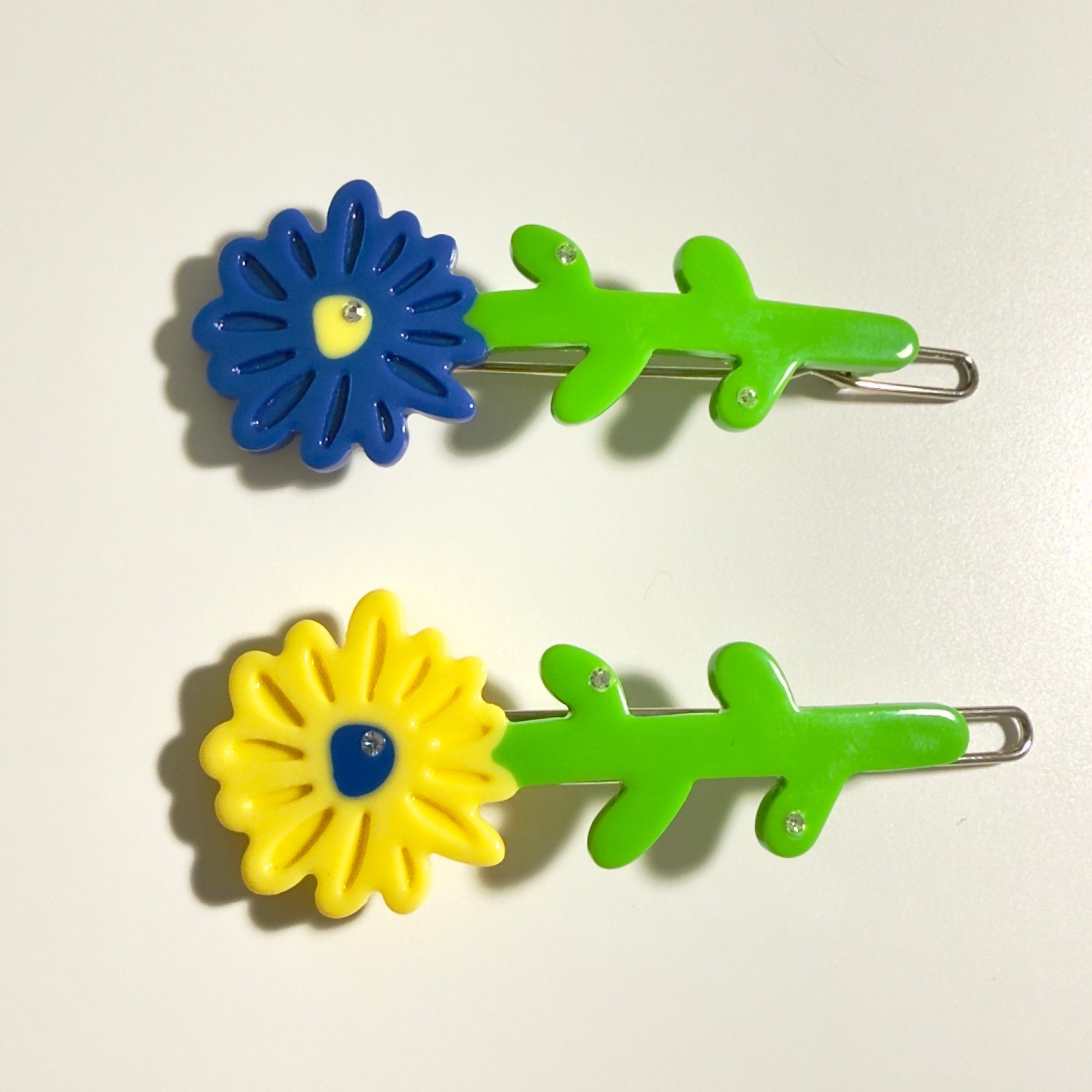 Two pairs of colorful flower-shaped hair clips on a light background