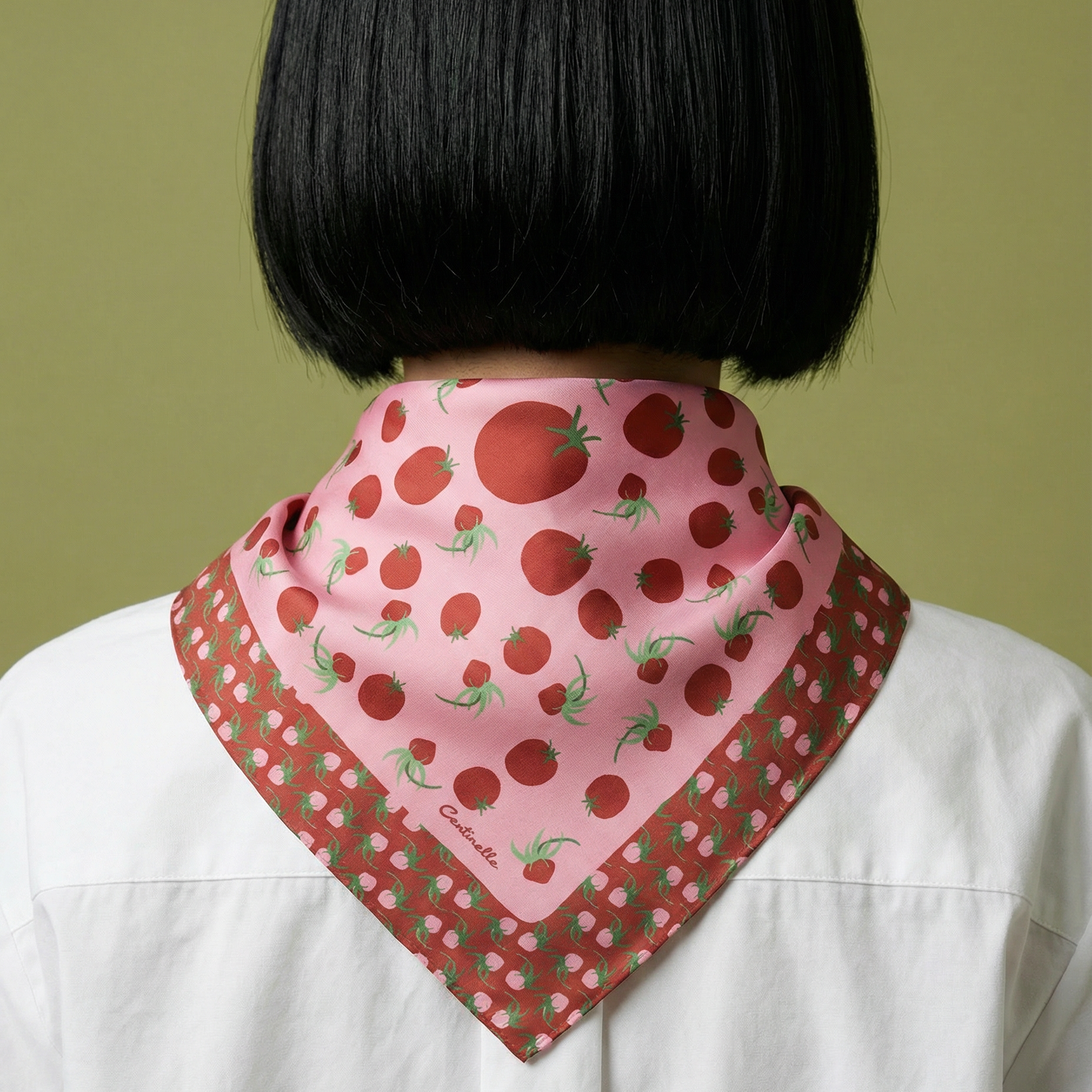 woman wearing a pink scarf with red tomatoes pattern on a green background