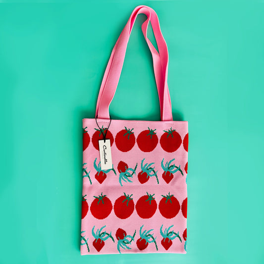 A pink centinelle knit tote bag with tomatoes on it.