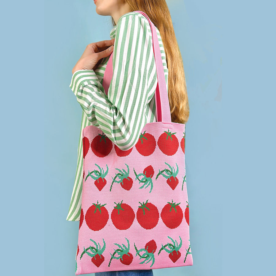 A pink centinelle tote bag with tomatoes on it.