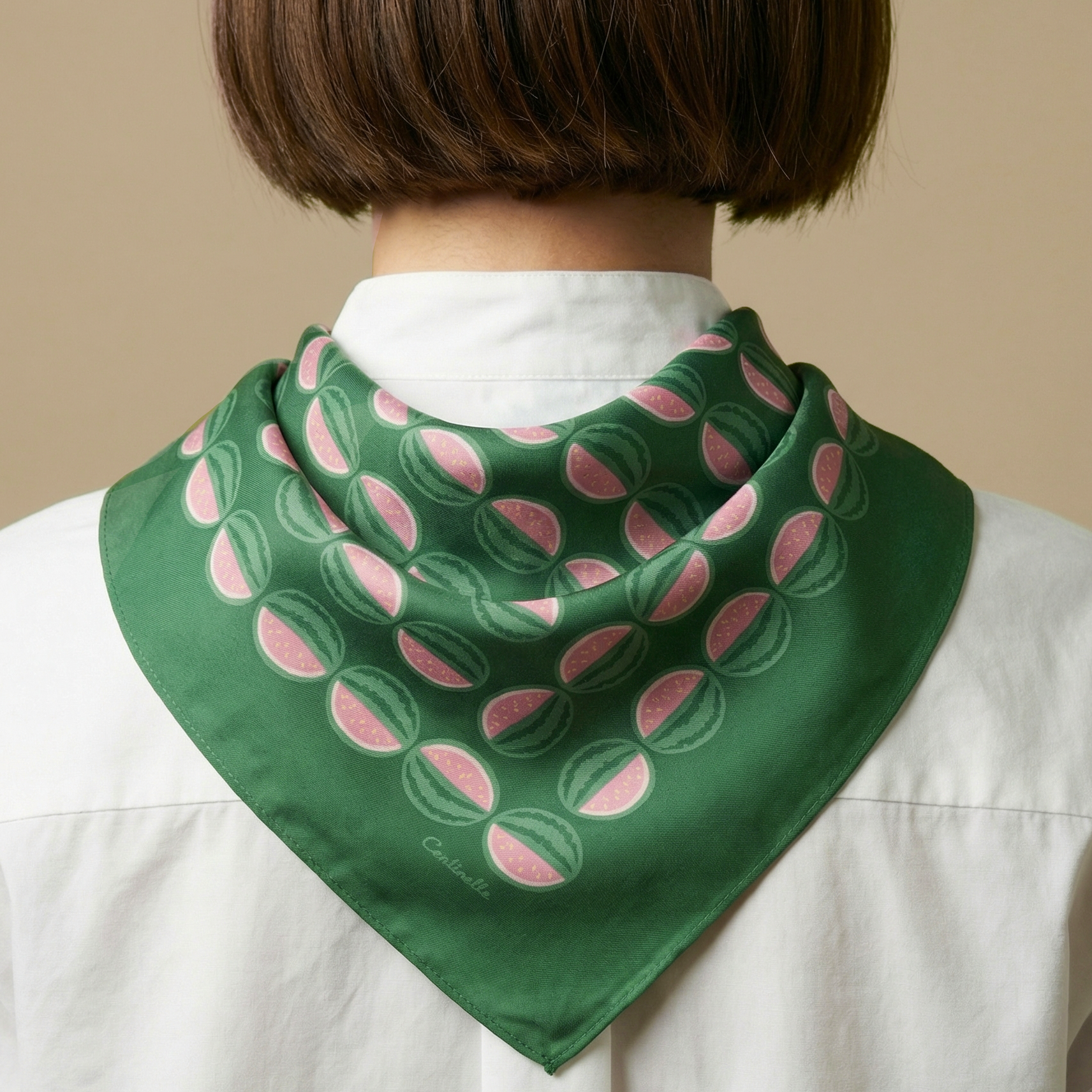 Person wearing a green watermelon with pink patterned bandana on a beige background
